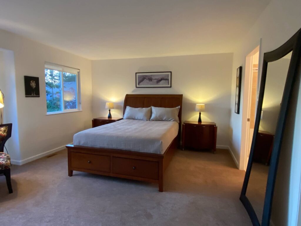 Master bedroom showing bed, tables, mirror and window