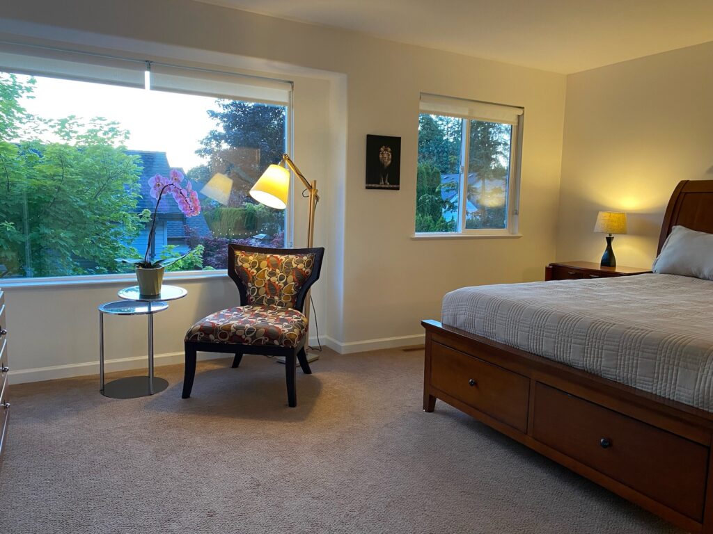 Master bedroom showing bed, chair and two windows