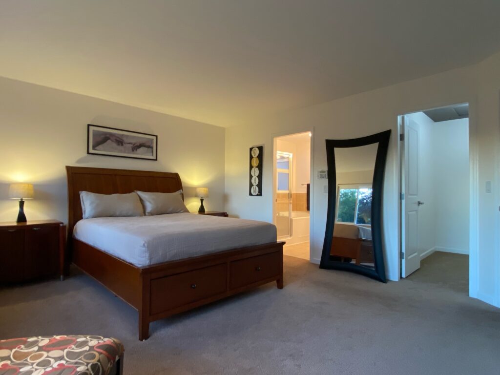 Master bedroom showing bed, wall mirror and master bath entrance