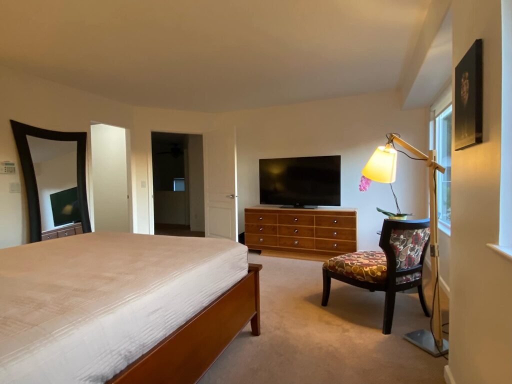 Master bedroom showing bed, chair, dresser and entrance doorway