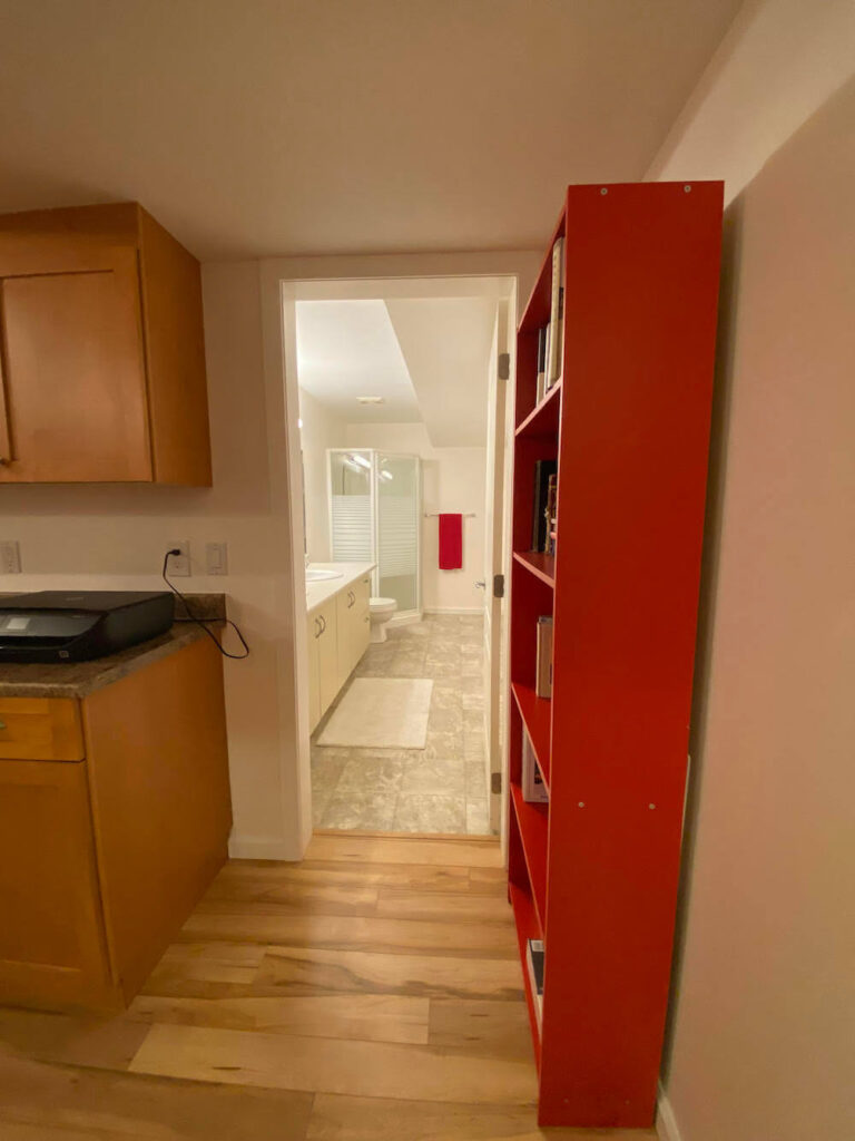 Doorway entrance to lower bathroom with red book stand on wall